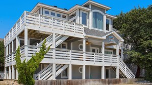 Ein mehrstöckiges Strandhaus mit Balkon, Pool und einem Schild, das auf einen nahegelegenen Park hinweist.