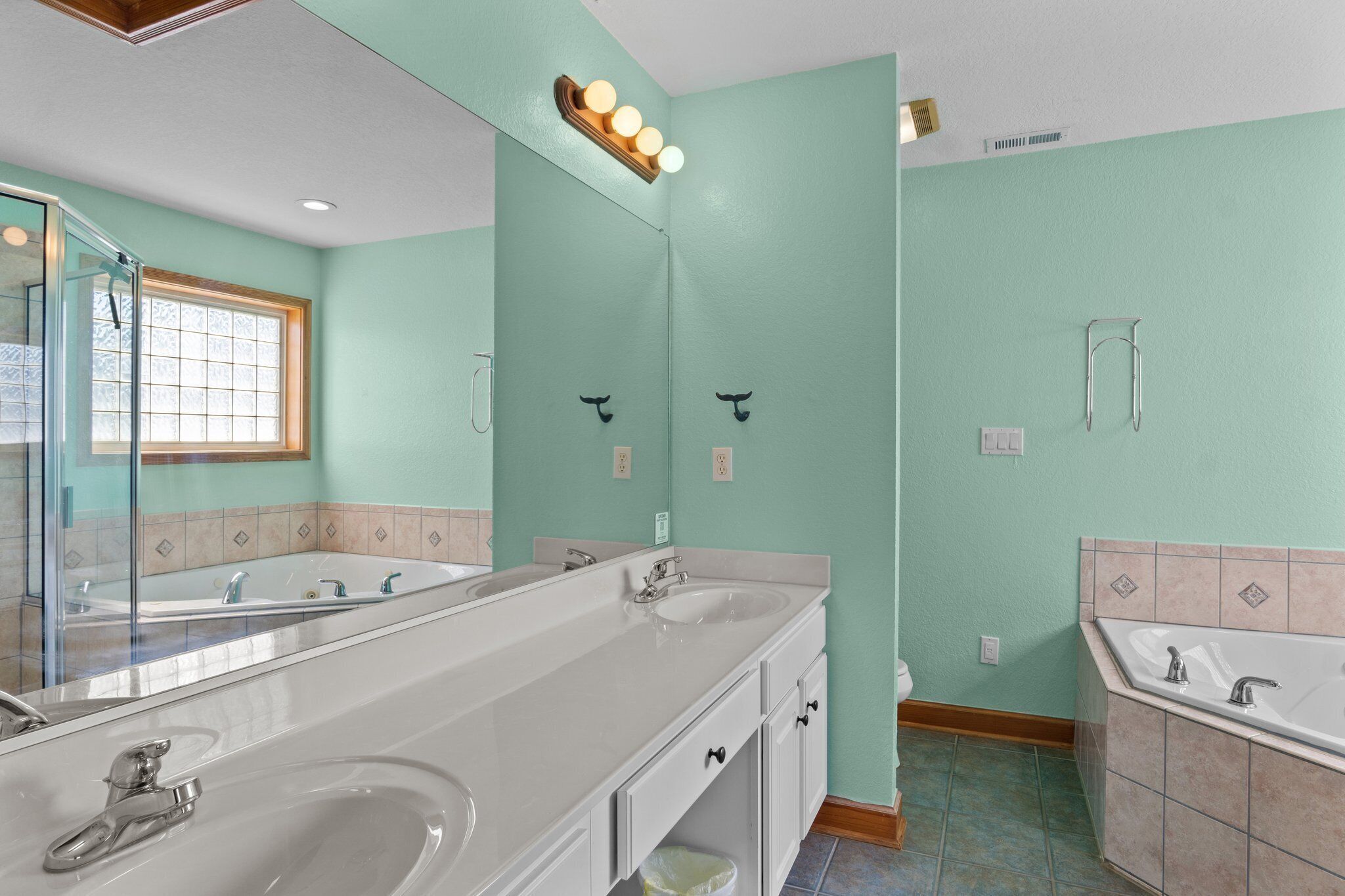Un baño con dos lavamanos, un espejo grande y una zona de ducha.