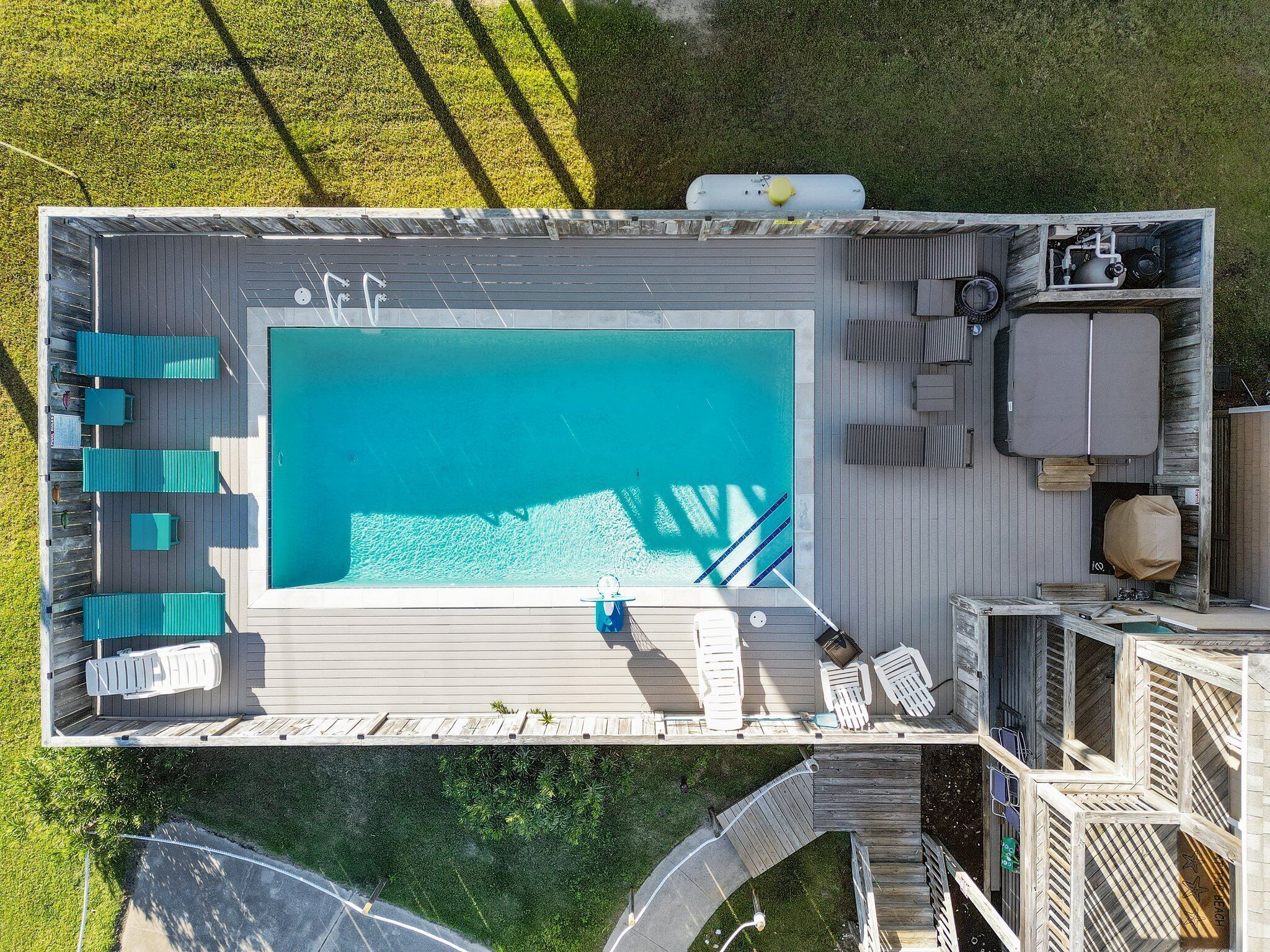 An aerial view of a swimming pool area with a deck, lounge chairs, and a covered seating area.