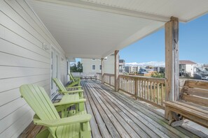 A wooden deck with green Adirondack chairs and a railing, overlooking a residential area with houses and mountains. - 5586- Gabe and Abe's Ocean Breeze - Dog-Friendly OBX Escape Near Nags Head Beach (Nags Head)