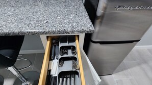 A kitchen with a granite countertop, a built-in stove, and a drawer organizer with utensils.