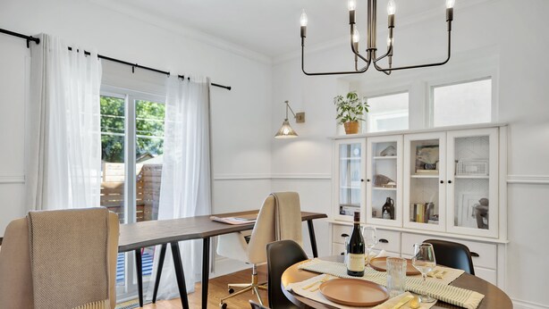 A dining area with a table set for two, a chandelier, and a cabinet with glass doors. - The Hipster House  (Windsor)