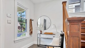 A room with a large window, a mirror, a shelf with books, and a chair. - The Hipster House  (Windsor)