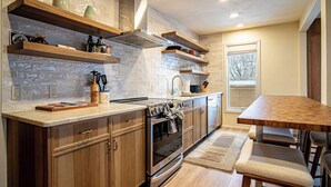 A modern kitchen with wooden cabinets, a built-in oven, and a dining area with a wooden table and chairs.