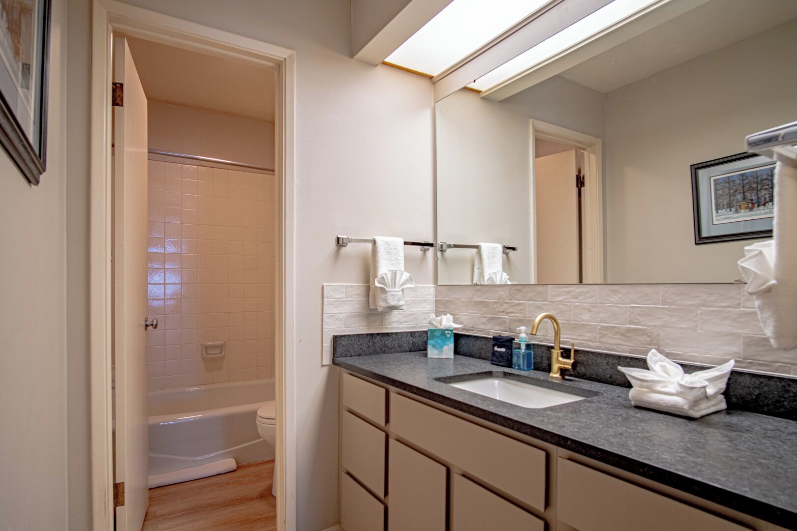 Un baño moderno con bañera, lavamanos y un espejo grande.