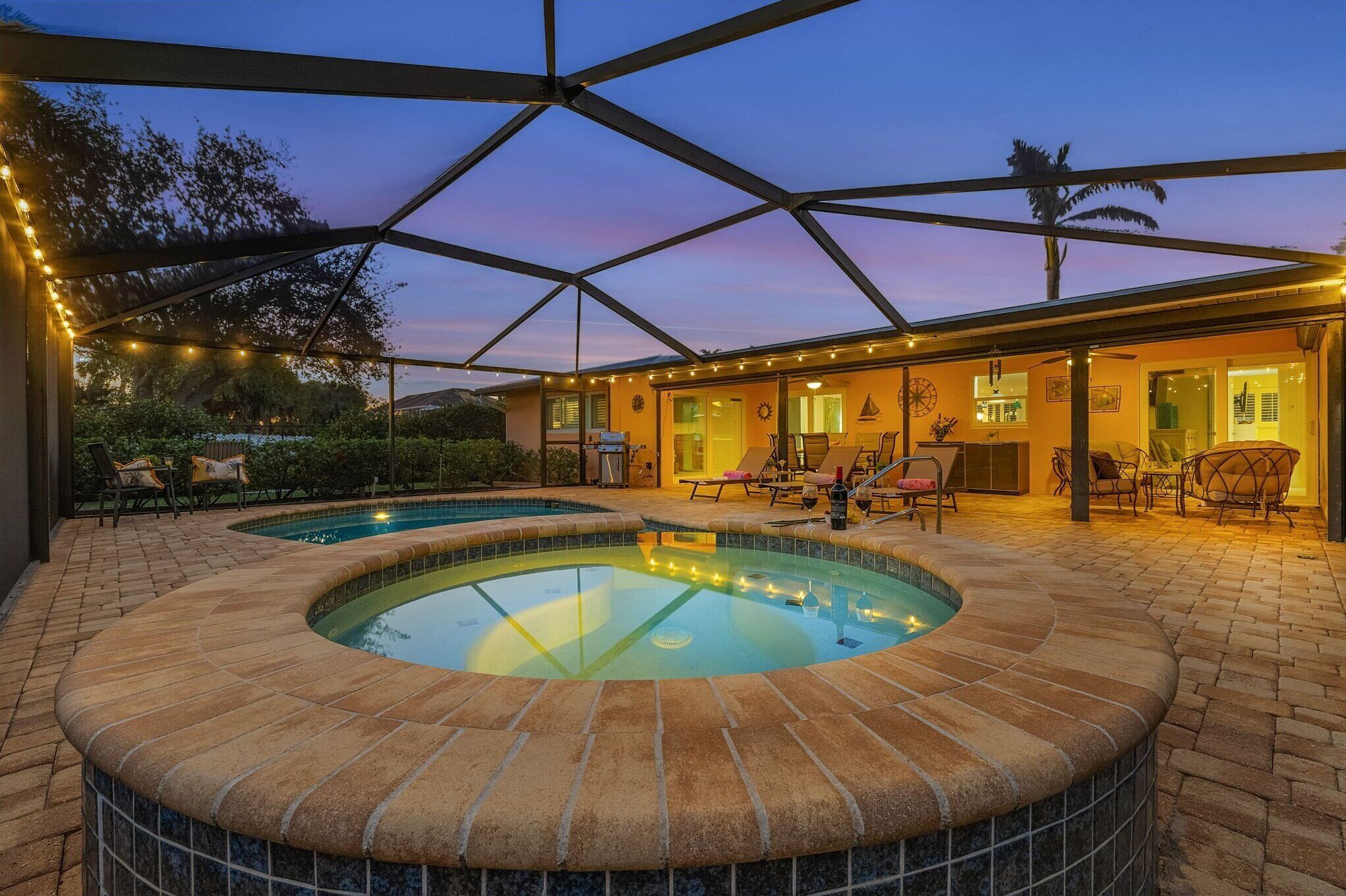 Un espace piscine comprenant un jacuzzi, des chaises longues et un patio couvert.