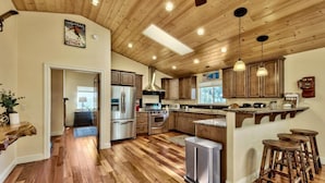 A spacious kitchen with wooden cabinets, stainless steel appliances, and a bar area with stools. - Lake Views and Mountain Luxury Lx66 (Zephyr Cove)