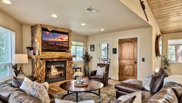 A cozy living room with a stone fireplace, leather sofas, and a television mounted on a wooden wall. - Lake Views and Mountain Luxury Lx66 (Zephyr Cove)