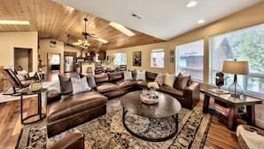 A spacious living room with a large sectional sofa, a round coffee table, and a dining area in the background. - Lake Views and Mountain Luxury Lx66 (Zephyr Cove)
