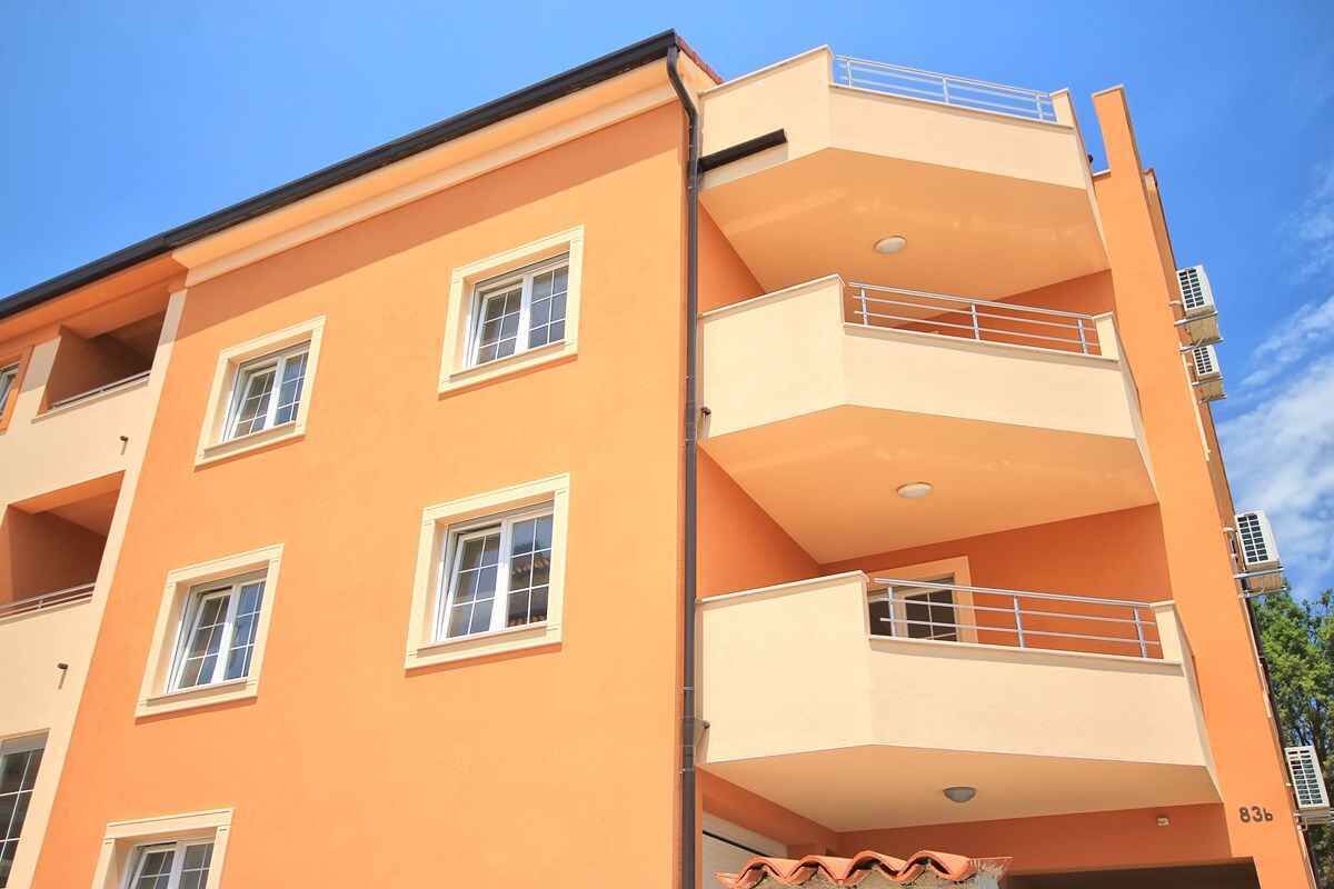 Um edifício com vários andares, varandas, janelas e aparelhos de ar condicionado.