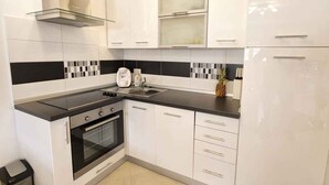 A modern kitchen with white cabinets, black countertops, a stainless steel range hood, and a built-in oven. - Holiday apartment with WiFi and balcony (Medulin)