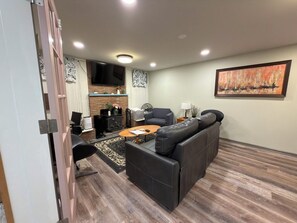A modern living room with a sectional sofa, a coffee table, and a flat-screen TV mounted on the wall. - West Seattle 2BR+ Heated Floors & Free Parking (Seattle)