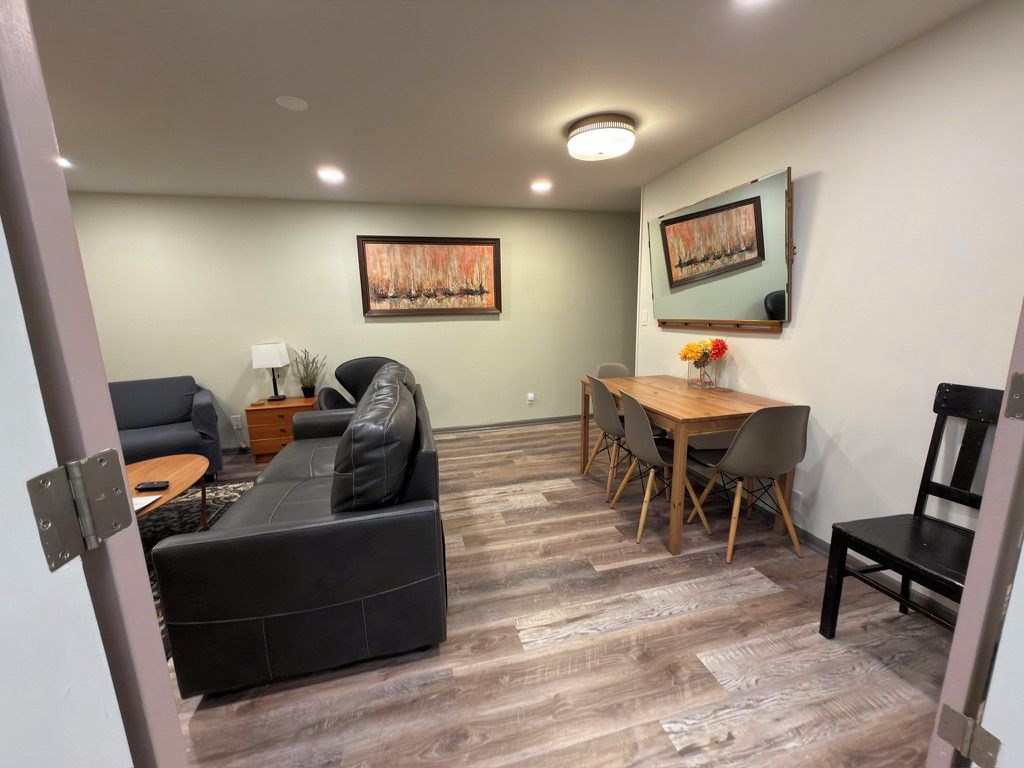 Een woonkamer met een bank, een eettafel met stoelen, een salontafel en kunstwerken aan de muur.