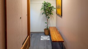 A narrow hallway with a wooden door, a bench, a potted plant, and a framed picture on the wall. - Seaview Hideaway 2BR Near Alki Beach & Stadiums (Seattle)