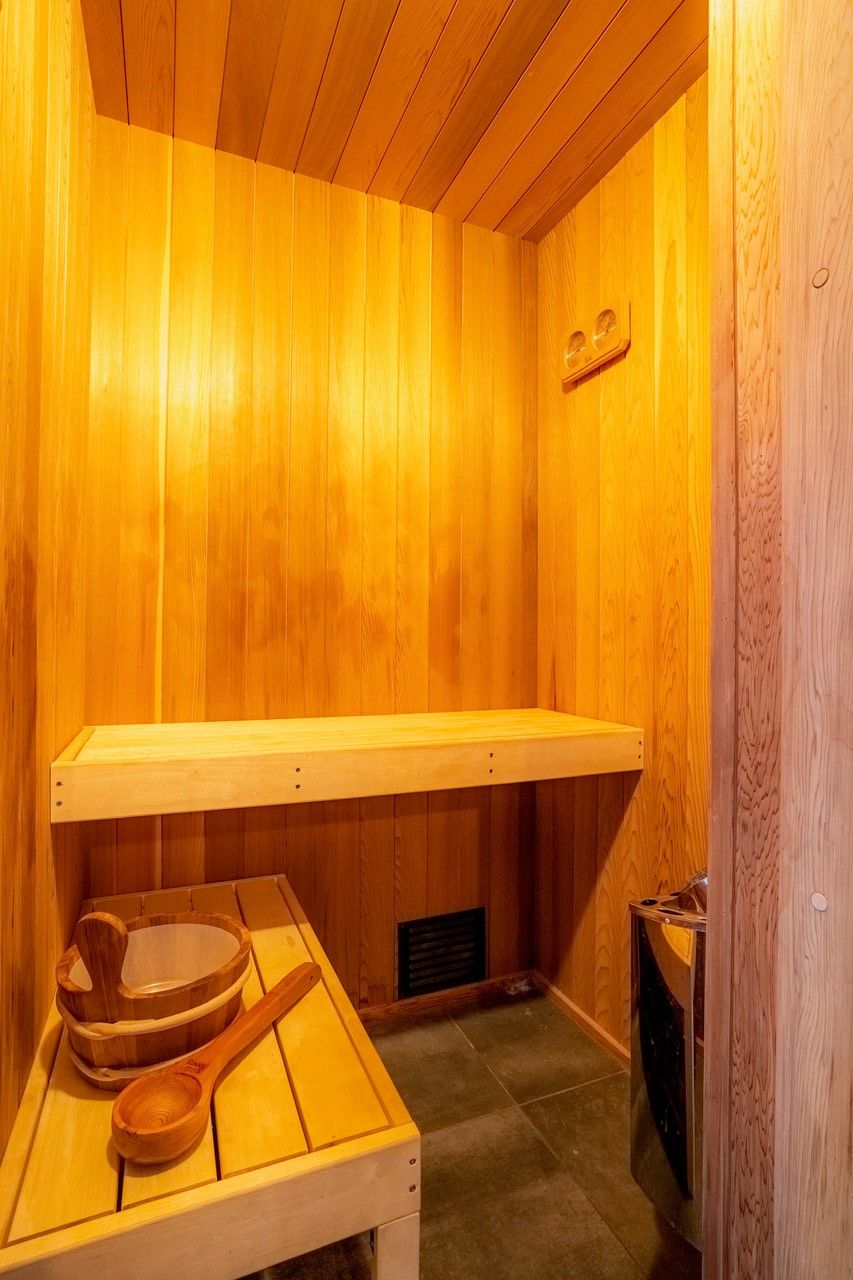A wooden sauna room with a bench, wooden bowls, and a wooden spoon.