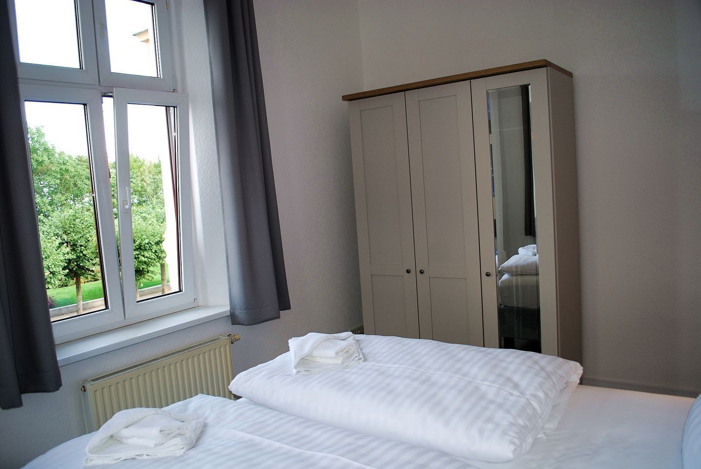 A bedroom with a bed, a wardrobe, and a window with curtains.