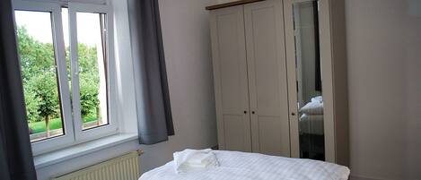 A bedroom with a bed, a wardrobe, and a window with curtains.