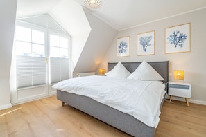 Ein Schlafzimmer mit einem großen Bett, einem Oberlicht und drei gerahmten Wandbildern.