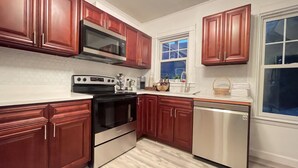 A modern kitchen with dark wooden cabinets, stainless steel appliances, and a white countertop. - Beautiful Victorian home, Great view with balcony. Free parking. (Boston)