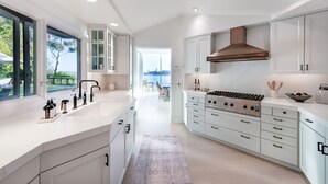 A modern kitchen with white cabinetry, a large island, and a view to the outdoors. - Stunning Panoramic views of SF, Bay/GG Bridge, Sausalito, Mt. Tam in  Belvedere (Belvedere)