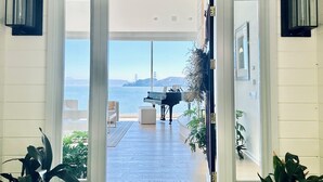 A grand entrance with a view of the ocean and a piano, leading to a spacious interior with a high ceiling and potted plants. - Stunning Panoramic views of SF, Bay/GG Bridge, Sausalito, Mt. Tam in  Belvedere (Belvedere)