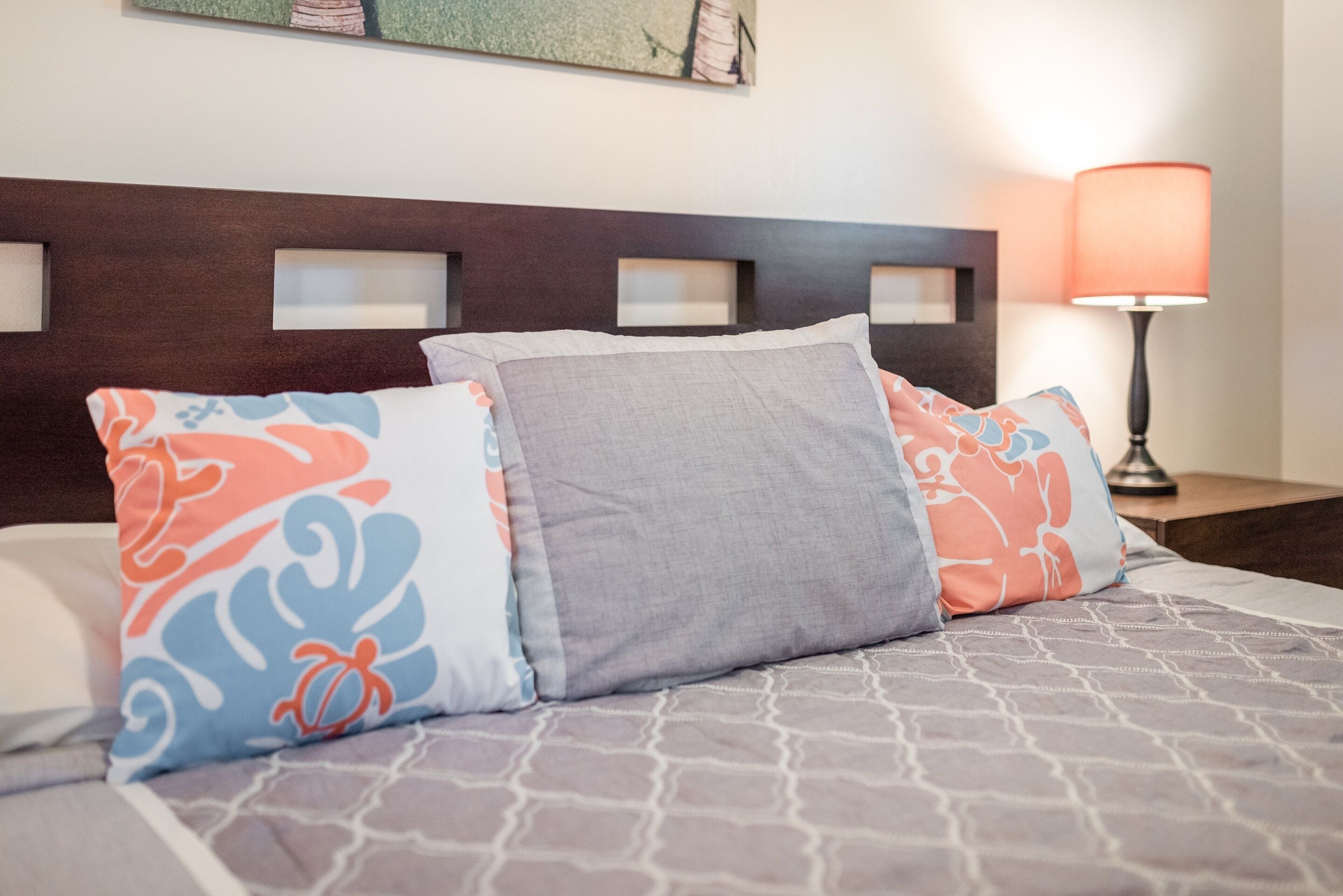 A bed with patterned bedding, a headboard with built-in shelves, and a bedside lamp.