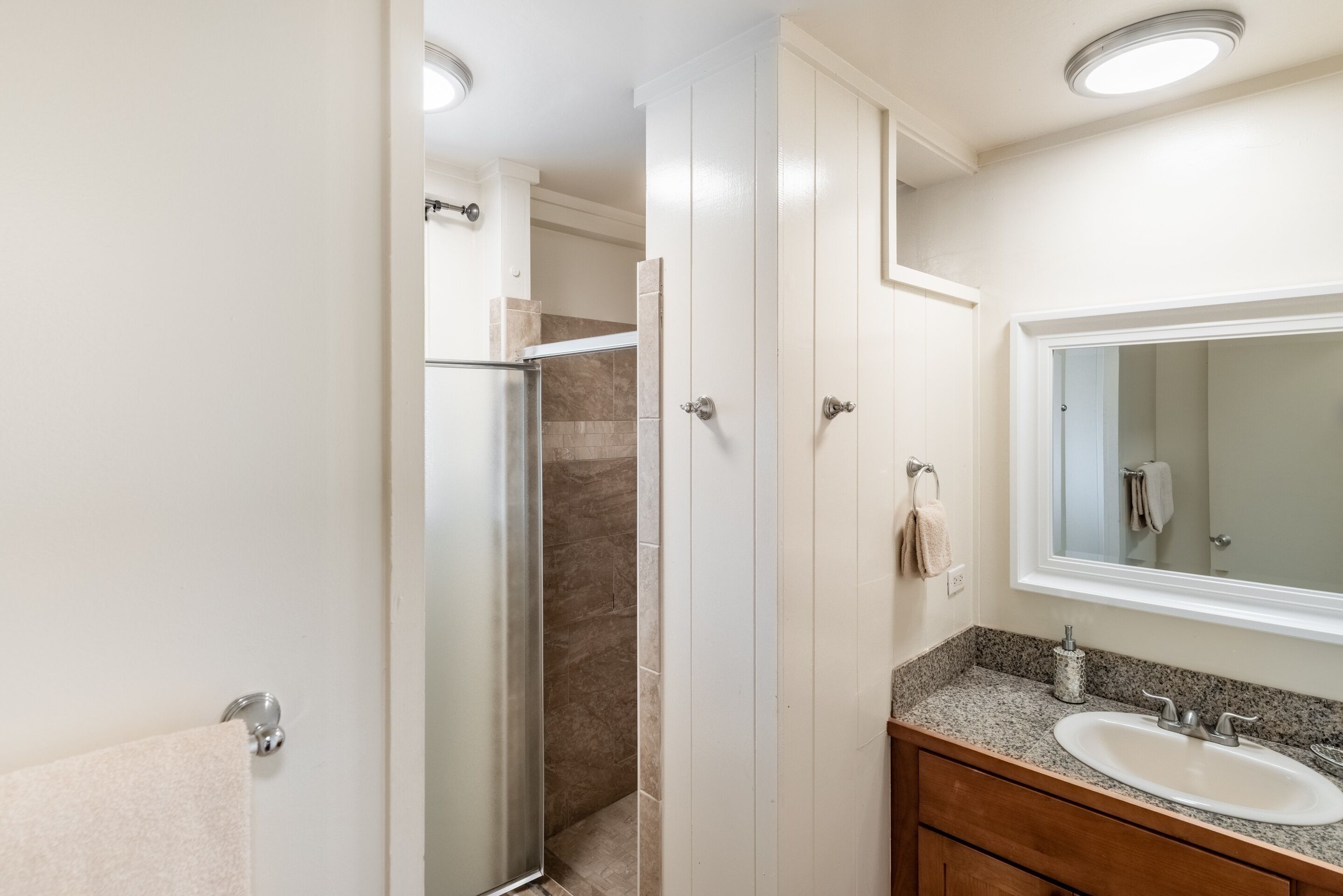 A bathroom with a shower, a sink, and a mirror.