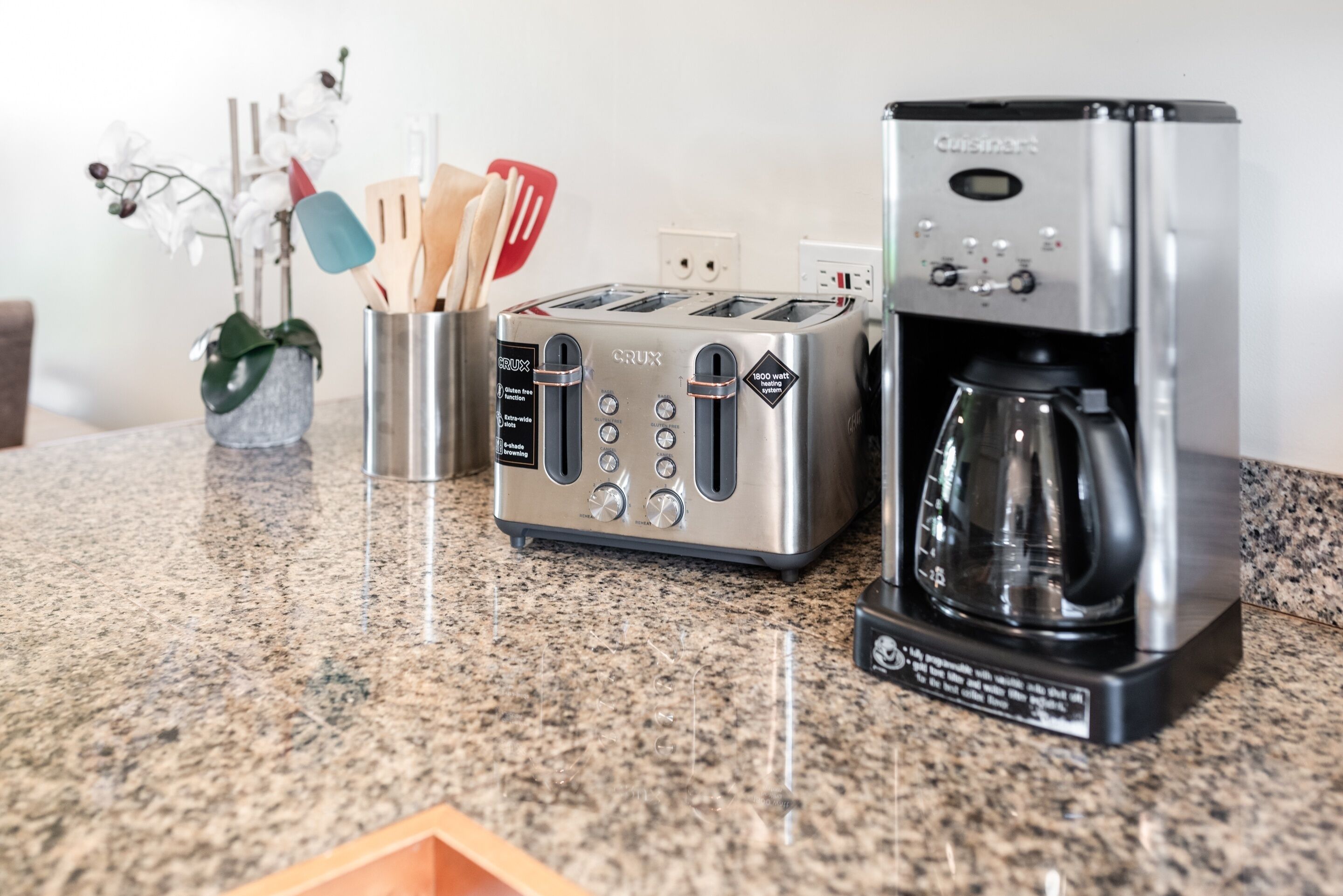 Une cuisine équipée d’un grille-pain, d’une machine à café et d’un porte-ustensiles.