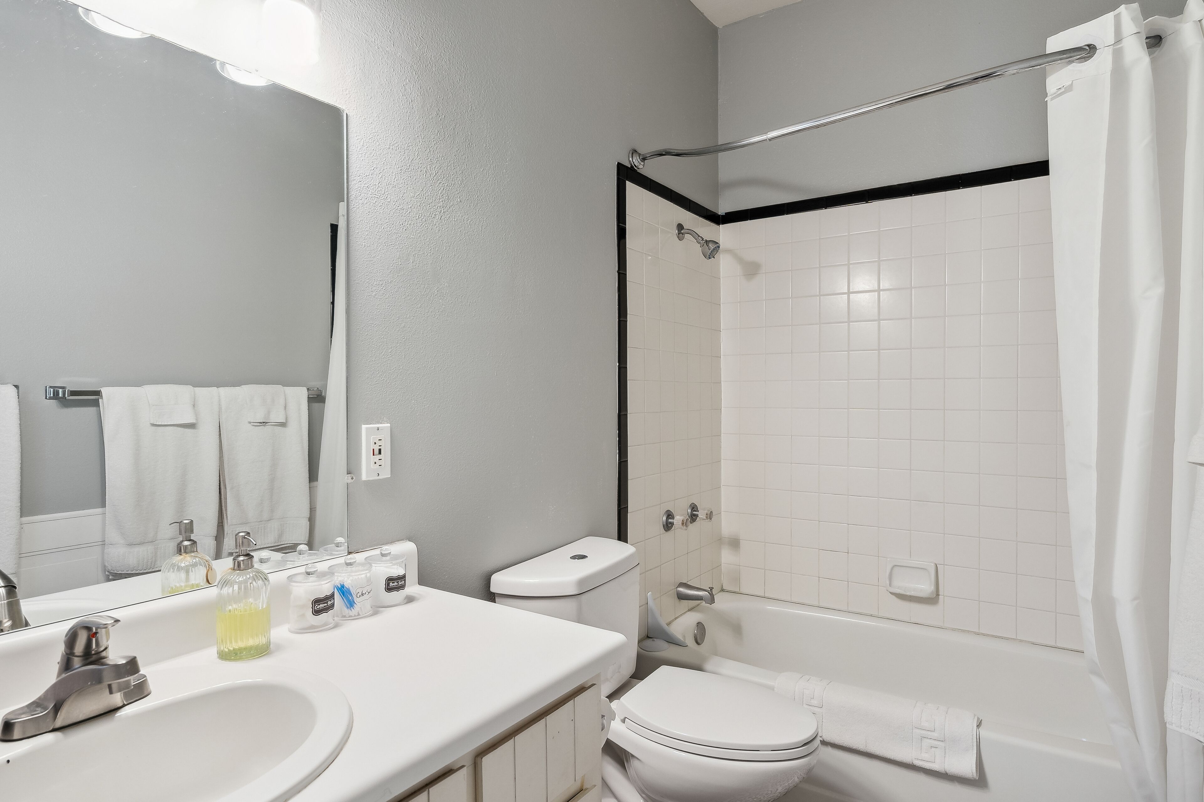 A bathroom with a sink, mirror, toilet, and bathtub.