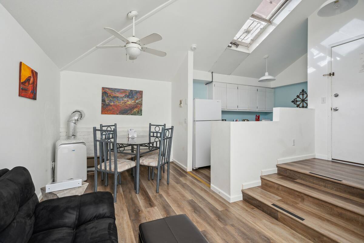 A compact living space with a dining area, kitchenette, and a staircase leading to an upper level.