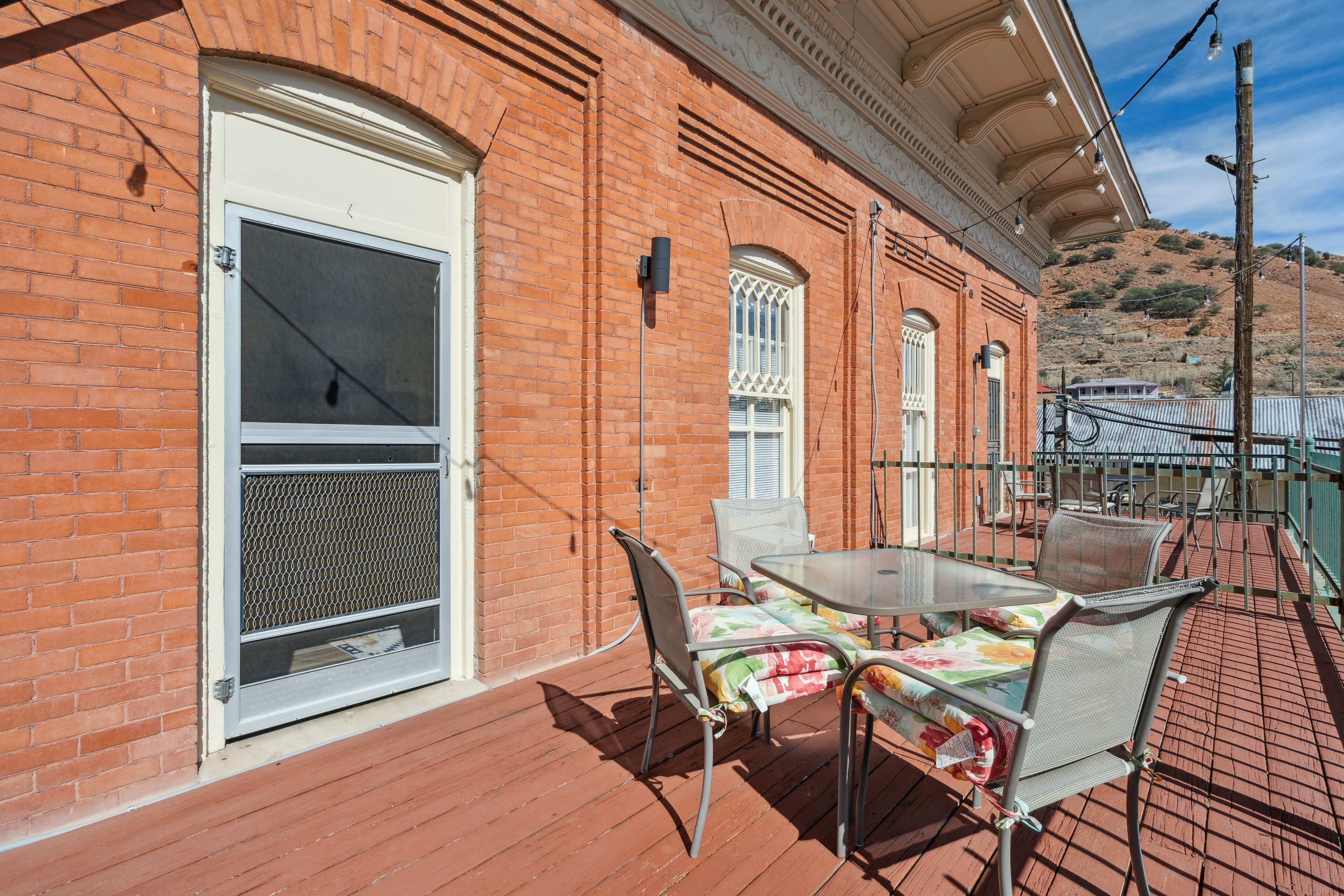 A patio with a table and chairs, a brick wall, and a door with a window.