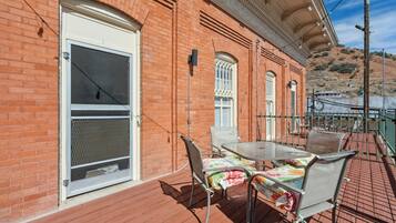 A patio with a table and chairs, a brick wall, and a door with a window.