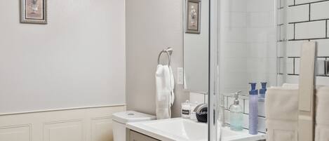 Une salle de bain comprenant des toilettes, un lavabo et un espace douche.