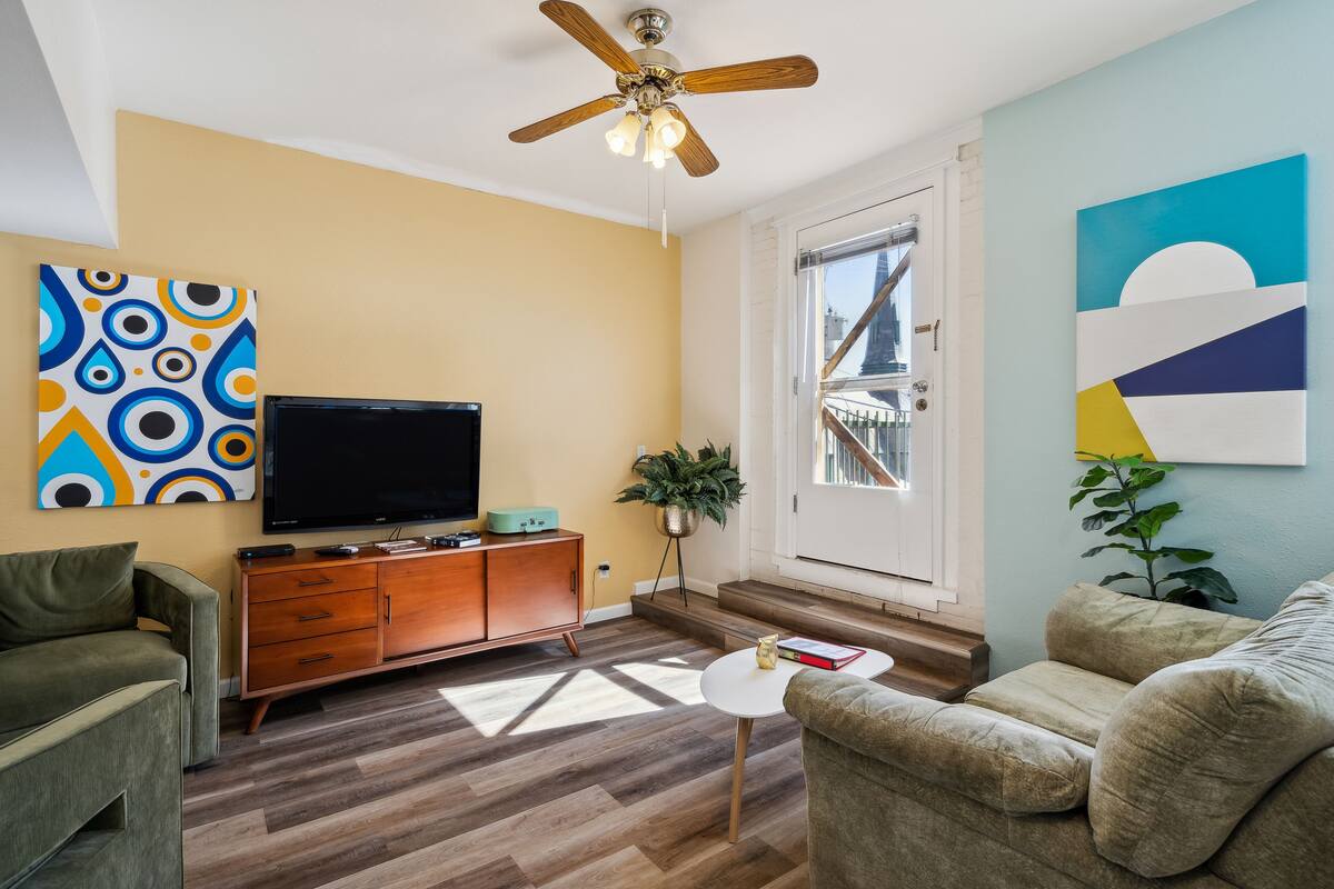 A living room with a television, sofa, and a ceiling fan.