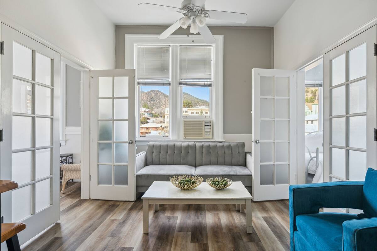 A spacious room with a grey sofa, a white coffee table, and a blue armchair.