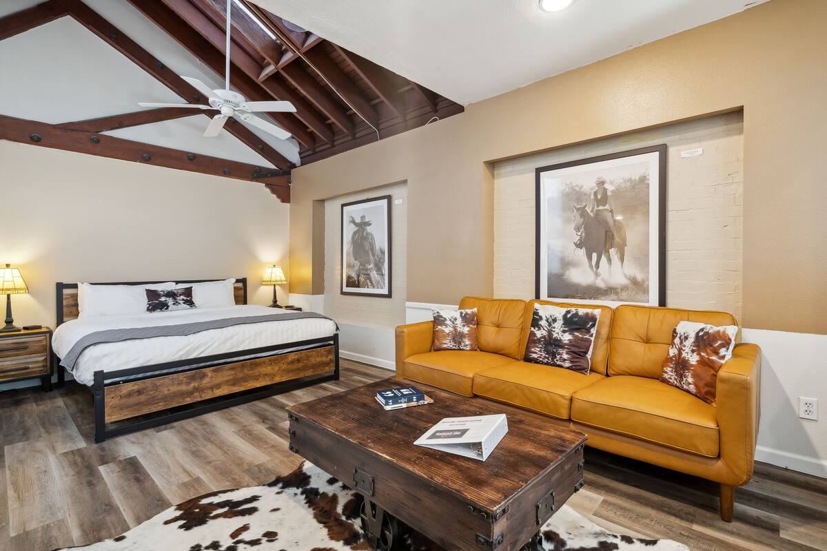 A bedroom with a bed, a wooden headboard, a yellow sofa, and a rustic coffee table.
