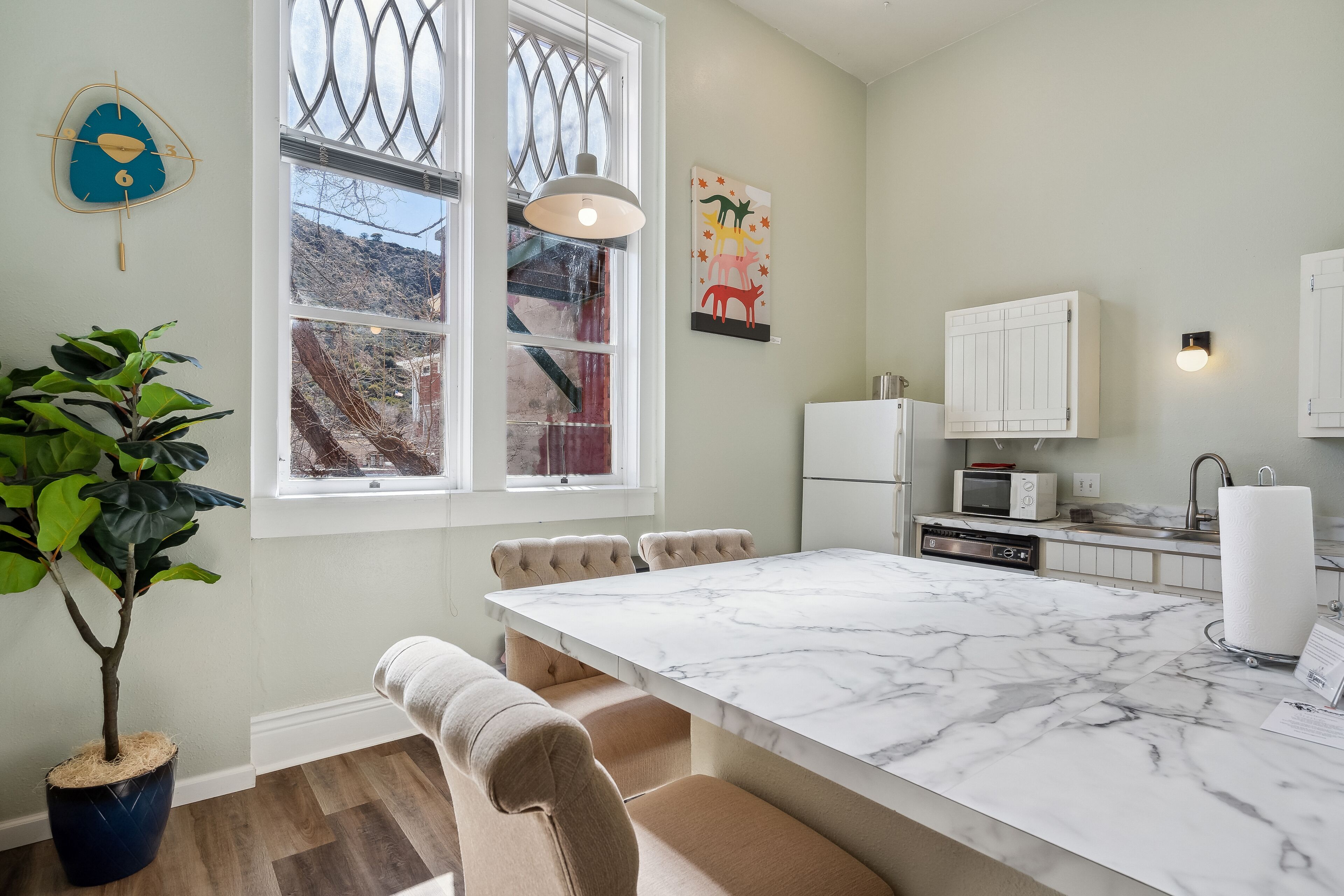A modern kitchen with a marble countertop, white cabinets, and a dining area with a table and chairs.