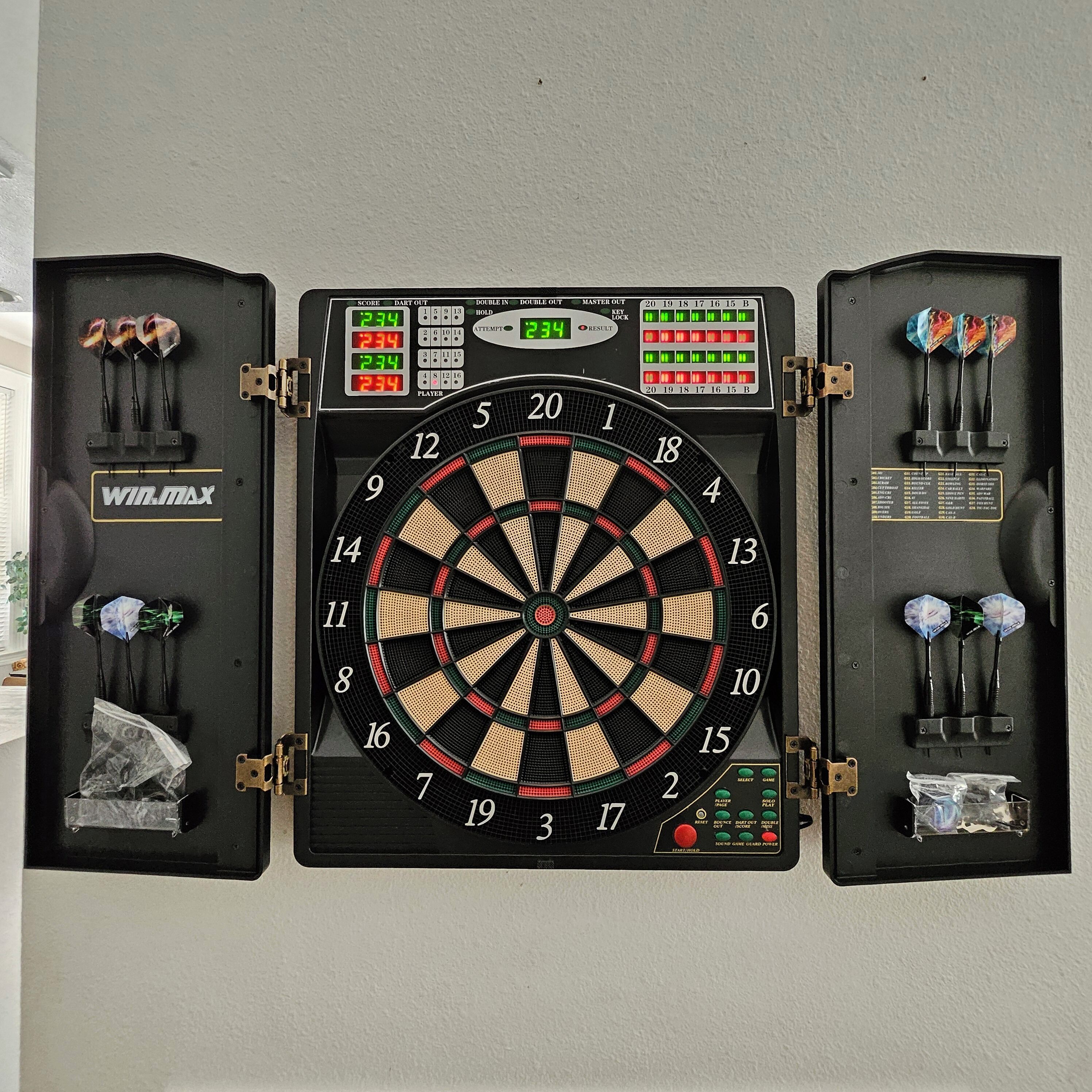 A dartboard with a score display and a dart case.