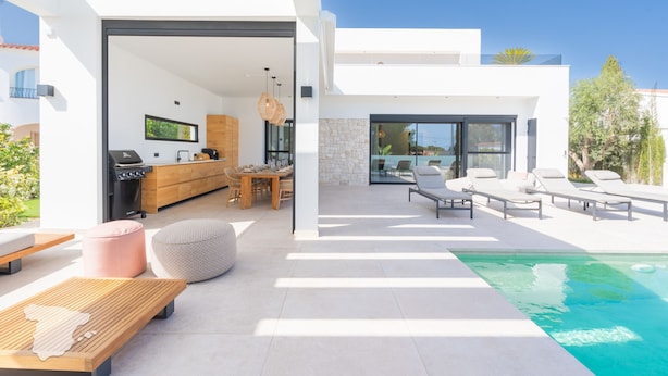 Un espacio exterior moderno con piscina, zona de comedor y cocina.