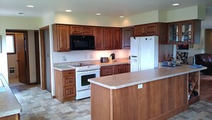 A modern kitchen with wooden cabinets, a white refrigerator, a stove, and a microwave. - Yellowstone River Retreat in Big Timber, Montana!! A few minutes from Downtown. (Big Timber)