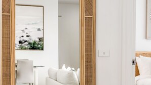 A modern room with a white sofa, a framed picture of a beach, and a door with a light switch. - Beach Break - Embrace the coastal lifestyle, with a view that will steal your breath away (East Ballina)