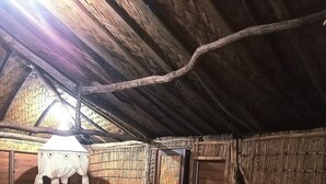 A rustic room with a thatched roof, wooden walls, and a bed with patterned bedding.