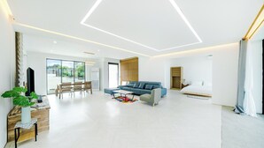 Ein modernes Wohnzimmer mit Sofa, Couchtisch und Essbereich.