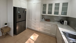 Een moderne keuken met witte kasten, een roestvrijstalen koelkast en een inbouwspoelbak.