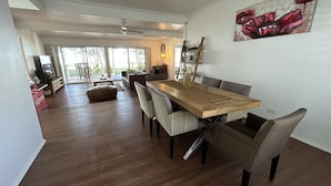 Een ruime eethoek met een houten tafel en stoelen, een groot raam en uitzicht op de omgeving.