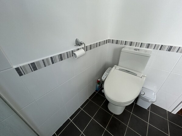 Une salle de bain moderne équipée de toilettes, d’un porte-rouleau de papier toilette et d’un bidet.