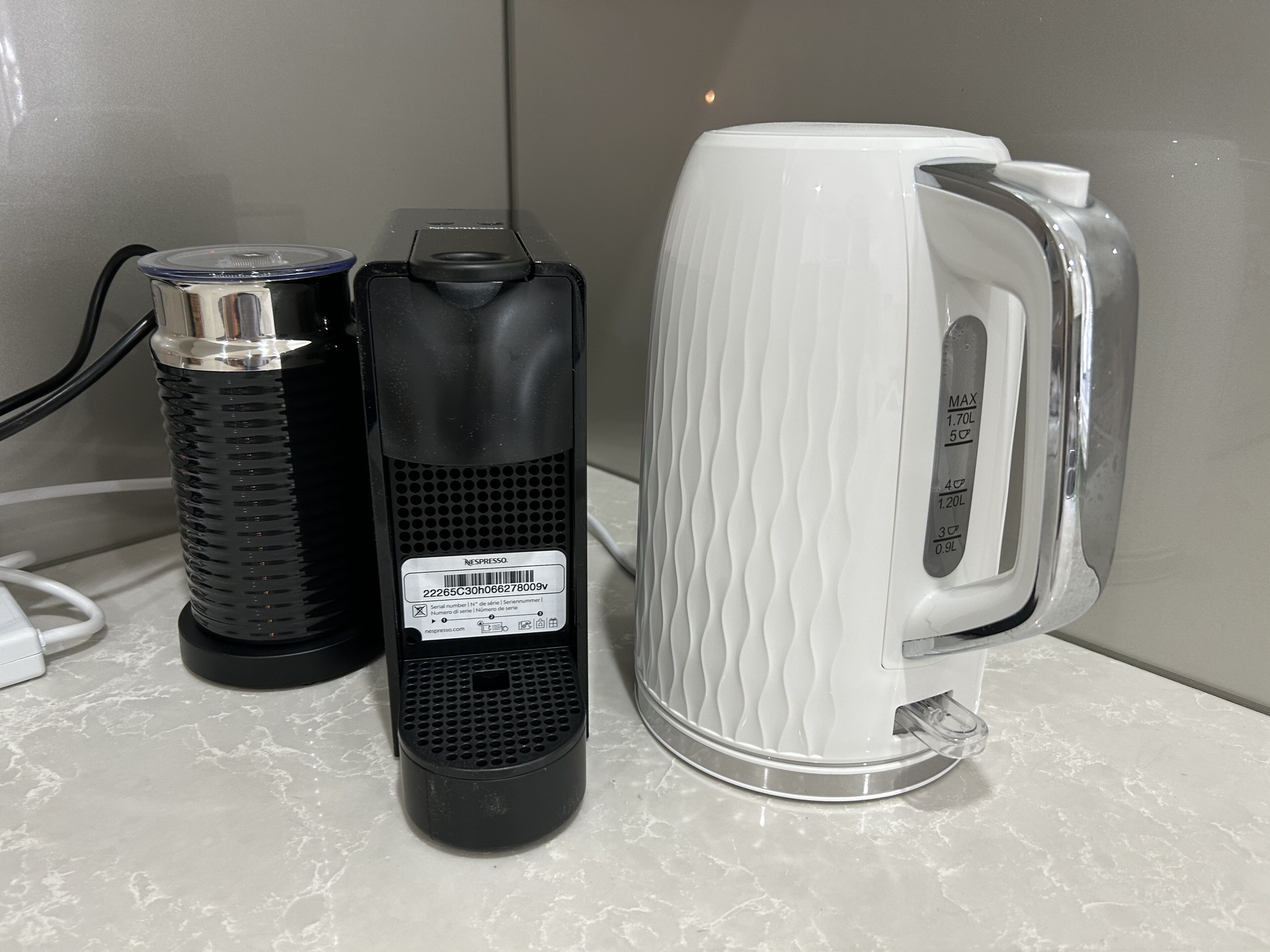 Une machine à café, une bouteille d’eau et un câble d’alimentation sur un plan de travail.