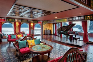 Un salón amplio con un piano de cola, asientos cómodos y ventanas grandes que ofrecen vistas panorámicas.