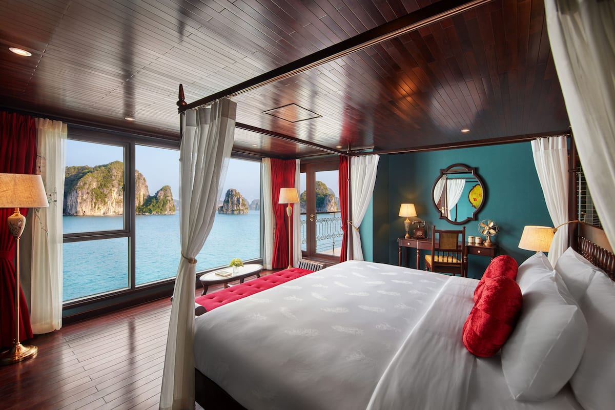 Een ruime kamer met een groot bed, uitzicht op zee en een houten plafond.
