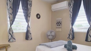 Un dormitorio con cama, ventilador y cortinas.